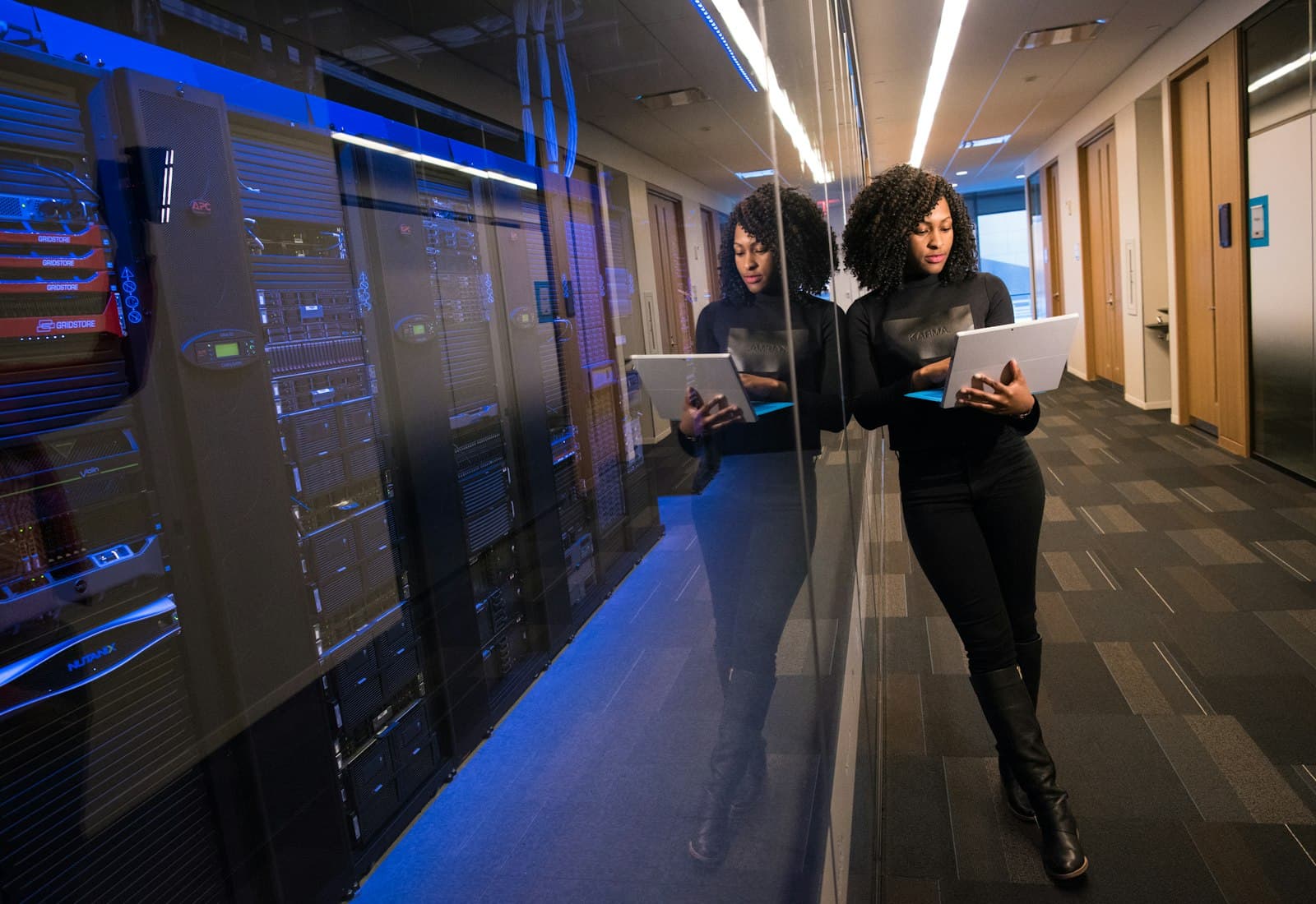 An engineer reviewing systems on a tablet beside racks in a data centre